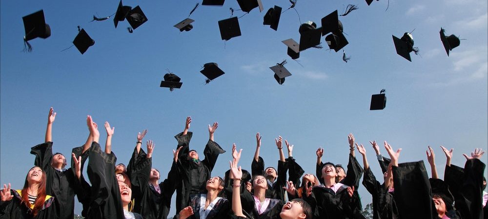 A group of graduates throws their caps in the air.
