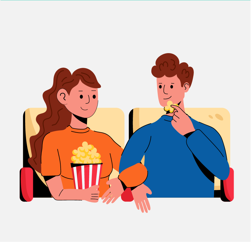 A couple sitting at the movies, eating popcorn, and linking arms.