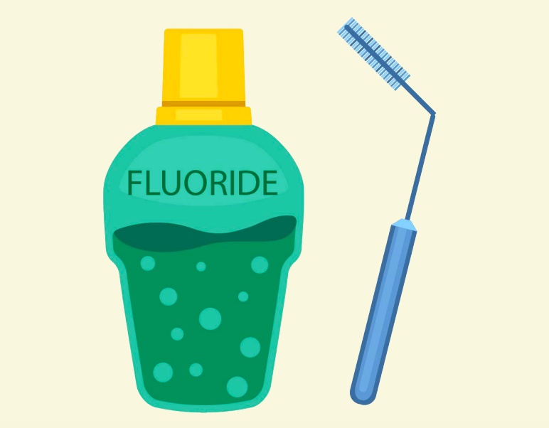 A bottle of fluoride next to a toothbrush.