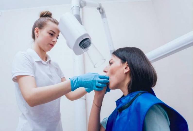 A dental assistant removing a dental holder from a woman's mouth.