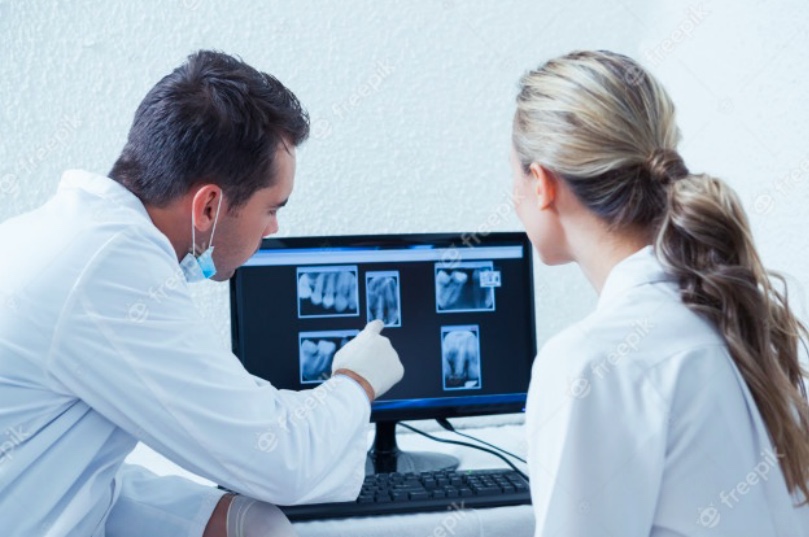 Dentists looking at x-rays on a computer.