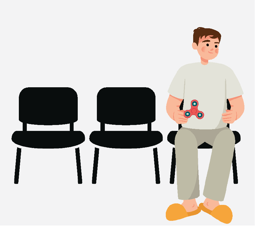 A man sitting in waiting room chairs and playing with a fidget spinner.
